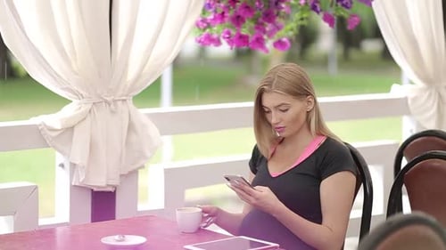 Smiling girl spending time in a street cafe using digital tablet