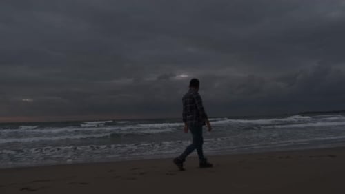 Man Walking on Beach at Sunrise