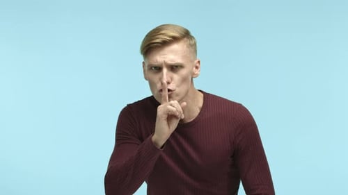 Young Adult Gesturing for Silence with Finger to Lips