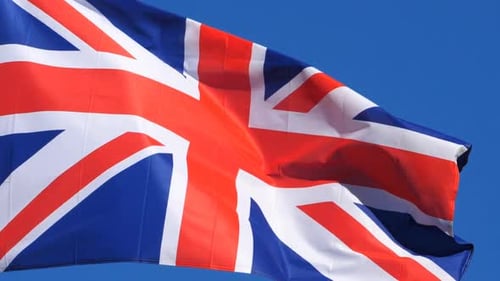 Union Jack Flag Waving Proudly Against Blue Sky