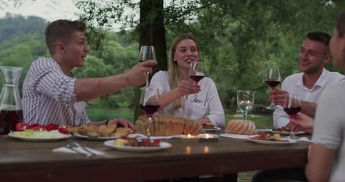 Friend Having Wine Beside River in the Countryside Enjoying Happy Moments