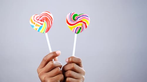 Hands Holding Two Heart Shaped Lollipops
