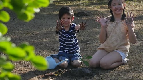 Boy and Girl Planting Tree Outdoors