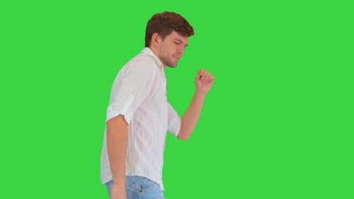 Joven alegre en ropa casual que baila alegremente mientras camina sobre una pantalla verde, Chroma Key.