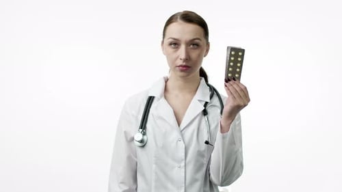 Smiling Doctor Holds Pills Against White Background