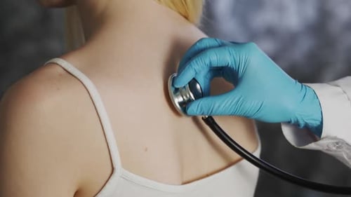 Doctor Listens to Young Adult's Back with Stethoscope