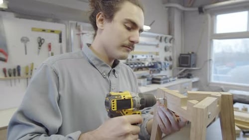 Man Assembling Wood Furniture with Power Drill