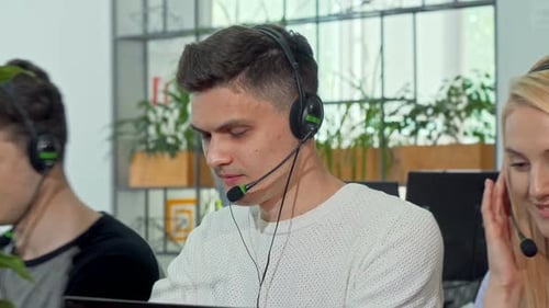 Young Man Working at Customer Support Call Center, Wearing Headset