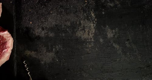 Two Raw Steaks with Rosemary on Dark Surface