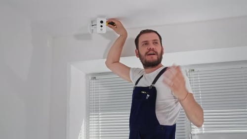Man Installs Security Camera on Ceiling Indoors