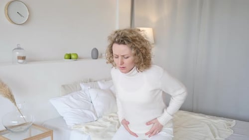 Junge schwangere Frau leidet zu Hause an Bauchschmerzen
