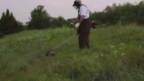 Side View of Man Keeping Electric Trimmer and Cutting Grass