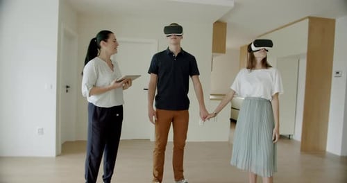 Estate Agent With Couple Wearing VR Headsets in New Apartment