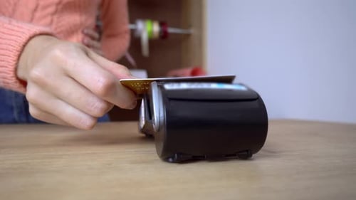 woman's hand holds plastic credit card in terminal. Payment by credit card.