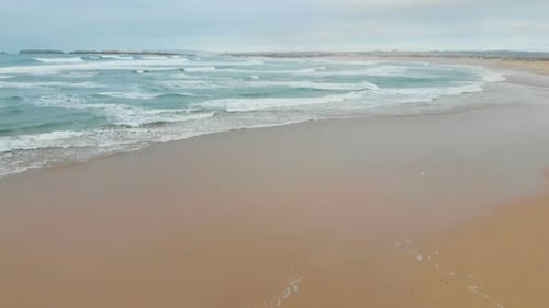 Aerial View of Sea Waves Break on Yellow Sand Beach