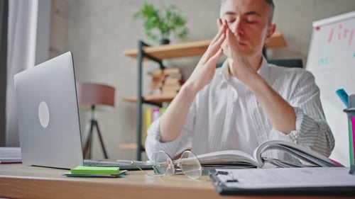 Middle Aged Man Taking Off His Glasses and Rubbing Nose Bridge Feeling Tired Working Online on