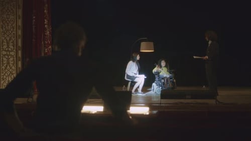 Three women on a stage with lighting technician