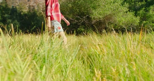 Side View of Traveler Woman in Denim Skirt and Classic Plaid Shirt on Meadow