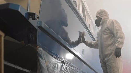 Factory Worker Wipes Down Large Machine in Suit