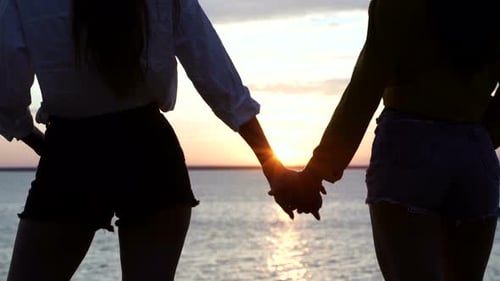 Romantic Couple Holding Hands at Sunrise by Ocean