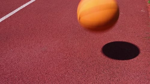 Ballon de basket dribble sur un terrain rouge