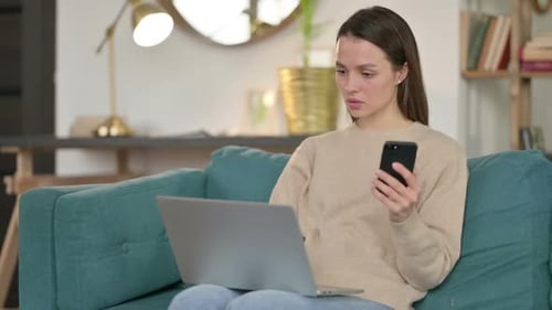 Woman Using Smartphone and Laptop at Home