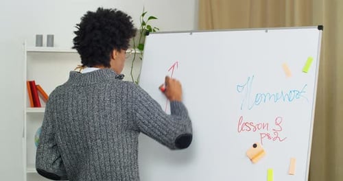 Portrait of Afro American Guy Student Young Math Teacher Tutor Stands at Blackboard Writes Draws