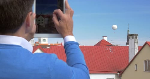 Man with Tablet Photographing City Rooftops
