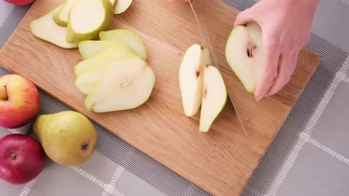 Cutting Slicing Fresh Pear with Knife on a Domestic Kitchen