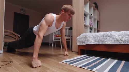 Young Adult Exercising Doing Pushups on Fists Indoors