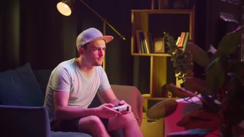 Man Plays Video Game on Couch at Night