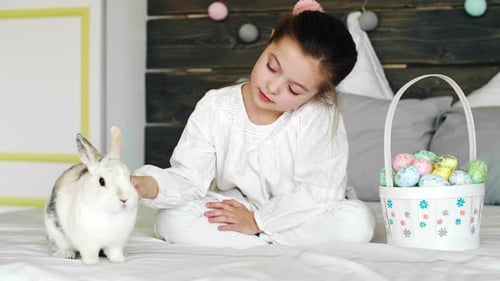 Girl and Bunny with Easter Eggs on Bed