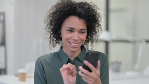 Smiling Woman Using Smartphone in Bright Office