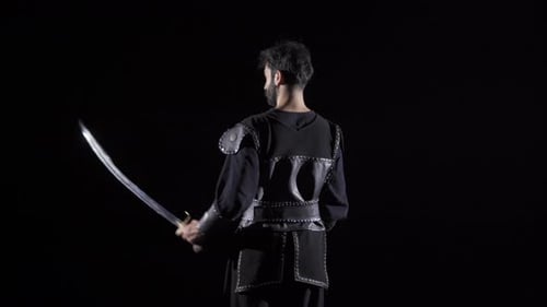 Man Wielding Sword in Dark Medieval Outfit