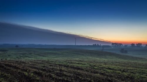 Stunning sunrise over a field with a windmill in autumn, timelapse, 4K