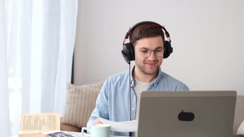 Man Waving at Computer During Video Call