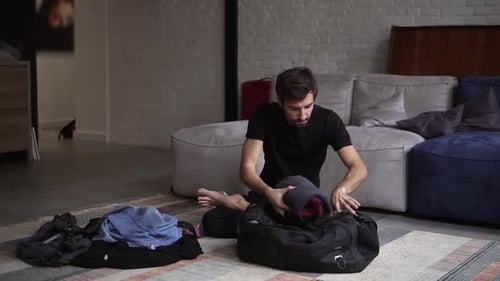 Man Packing Clothes into Duffel Bag at Home