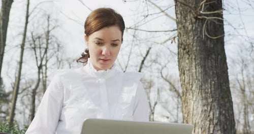 Woman Works On Laptop Outdoors in Park Setting