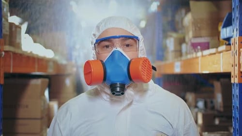 Masked Worker in Protective Suit in Warehouse