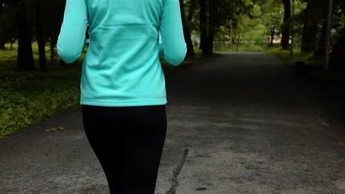 Happy Sporty Woman in Smal Headphone Outdoors in Park