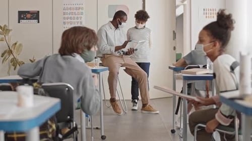 Teacher Helping Student in Elementary School Classroom