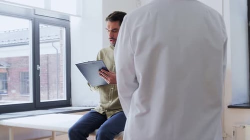 Male Patient Signing Papers and Doctor at Hospital