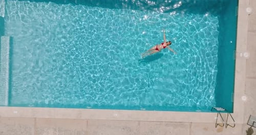 View From the Top As a Woman in a Yellow Swimsuit Lying on Her Back in the Pool