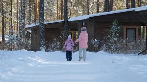 Child and Adult Walking in Snowy Winter Forest