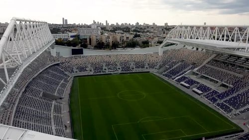 Aerial Static Respective shot of empty football stadium, City building in the background, drone shot