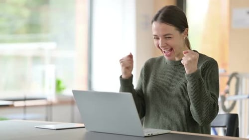 Young Woman Celebrating Success Using Laptop
