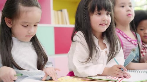 Multi-ethnic young boys and girls happy funny study and play painting on paper at elementary school.