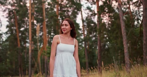 Beautiful and Happy Girl Walks Through the Forest in a White Dress