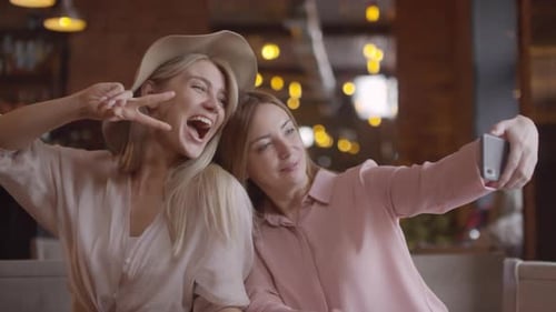 Happy Mother and Adult Daughter Taking Selfie in Cafe