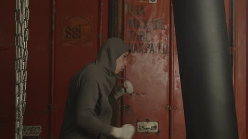 Aggressive Boxer Punching Boxing Bag Actively in Gym